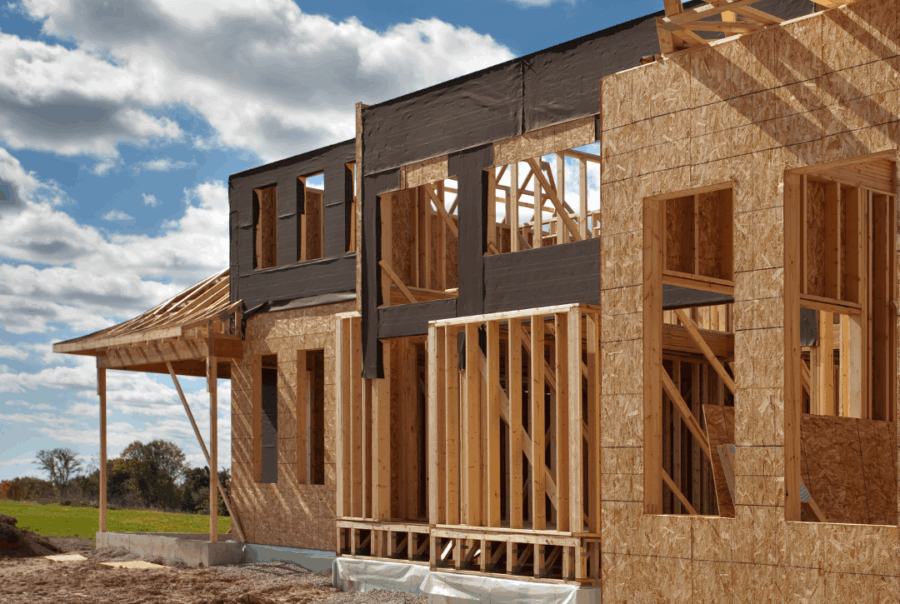 A two-story home under construction showing wood framing and OSB sheathing on the exterior.