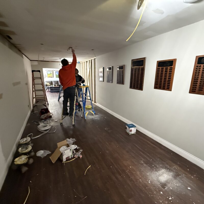 Construction crew installing ceiling lights in a hallway