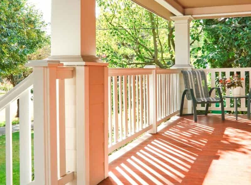 Beautiful covered front porch with wood flooring and white railing