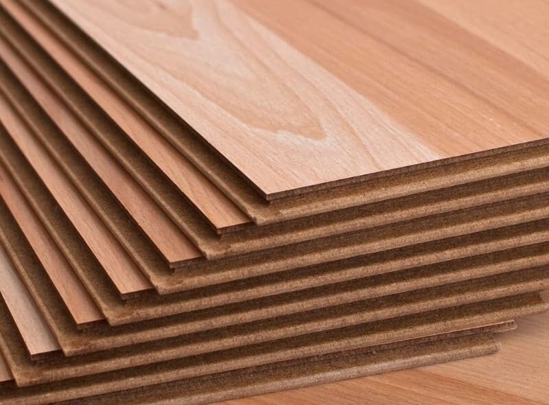 A stack of hardwood flooring planks displayed on a wood surface.
