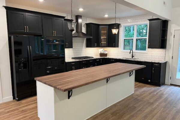 Remodeled kitchen featuring black shaker cabinets, a butcher block island, hexagon tile backsplash, and hardwood floors completed by Nova Construction and Remodeling.