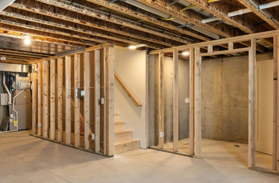Unfinished basement with wood stud framing and exposed pipes in a Central Missouri home ready for basement finishing by Nova Construction
